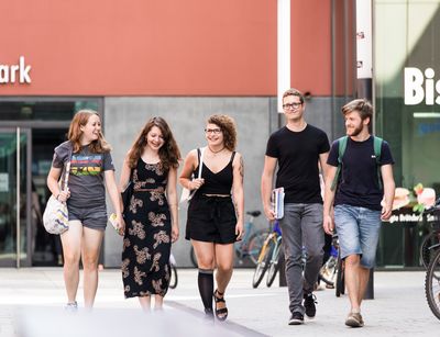 Studierende gehen nebeneinander auf dem Campusgelände