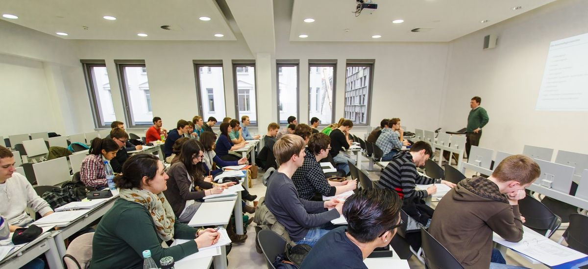 Studierende der Wirtschaftswissenschaftlichen Fakultät sitzen in Stuhlreihen und schauen zum Dozenten.