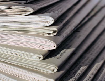 Part of a pile of newspapers photographed from the left corner upwards.