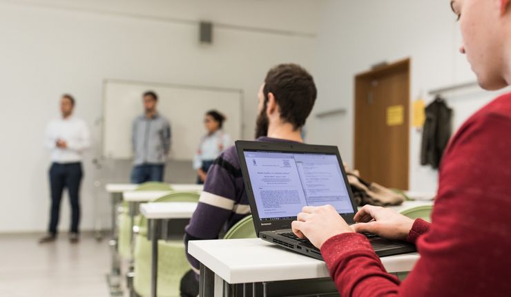 ein Student arbeitet während der Vorlesung an seinem Laptop