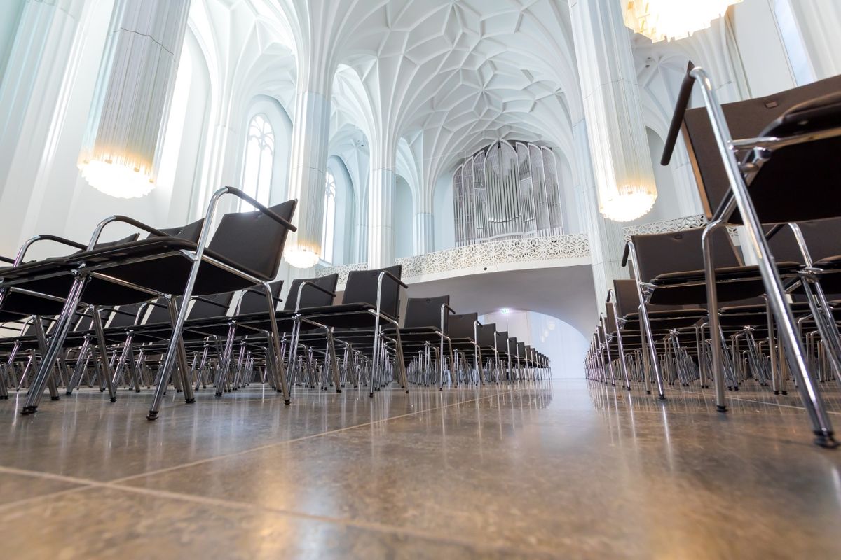 zur Vergrößerungsansicht des Bildes: Blick in den Innenraum des Paulinums; zu sehen sind die Stuhlreihen, die großen Fenster und die beleuchteten Glassäulen