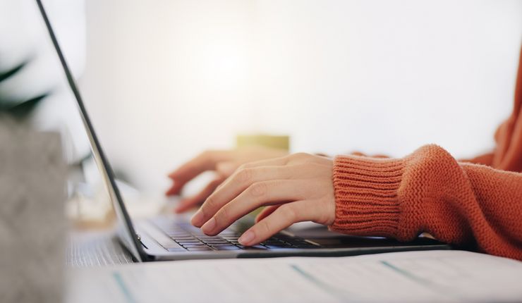 Person schreibt auf Tastatur vom Laptop, nur die Arme und Hände sind sichtbar