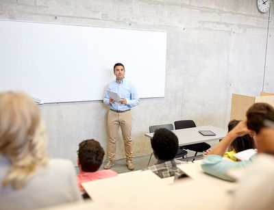 Dozent steht vor einer Gruppe Sturierender im Hörsaal