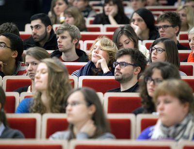 Eine Gruppe von Studierenden sitzen in einem Hörsaal und hören aufmerksam einer Vorlesung zu.