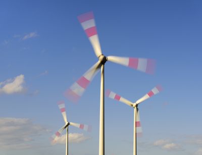 Dynamic photo of wind turbine blades turning against a blue sky.