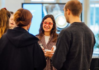 Pre-Doc Award Kick Off 2024 Frau, die eine Tasse hält, unterhält sich lächelnd in einer Gruppe von Menschen