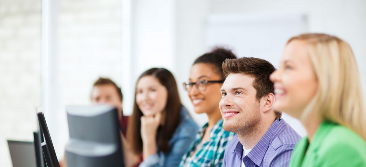 Studierende, die gemeinsam vor ihren Laptops sitzen und aufmerksam der Vorlesung folgen..